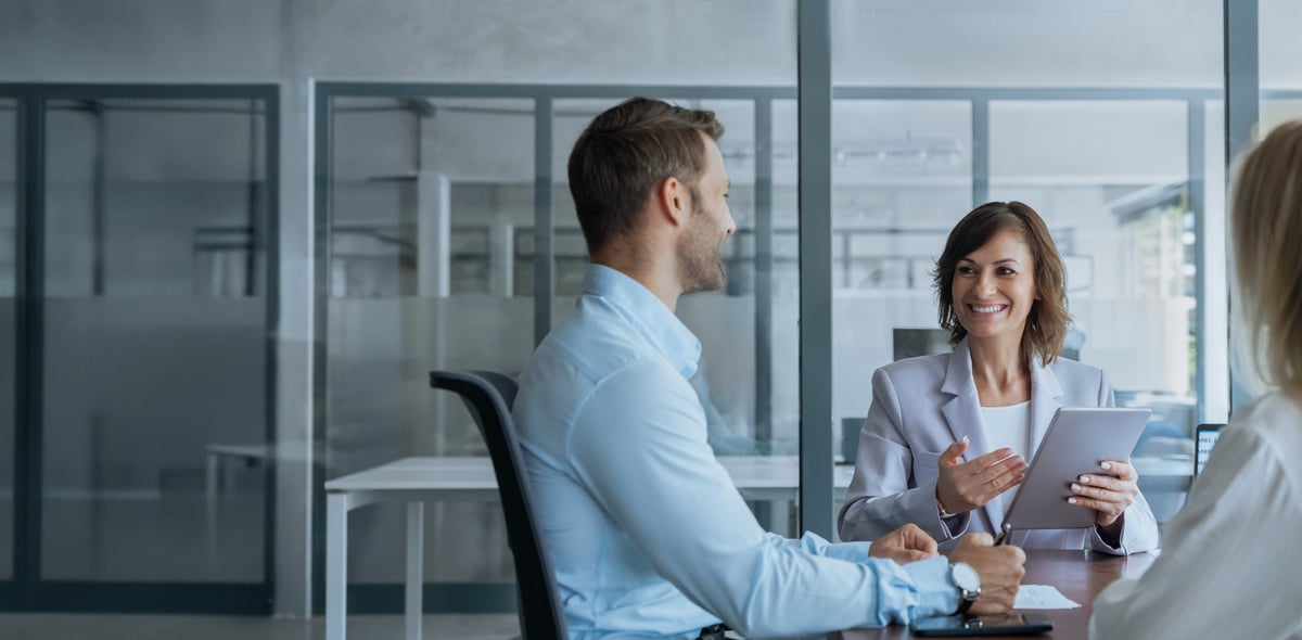An experienced business mentor reviewing a growth plan on a tablet with two younger colleagues